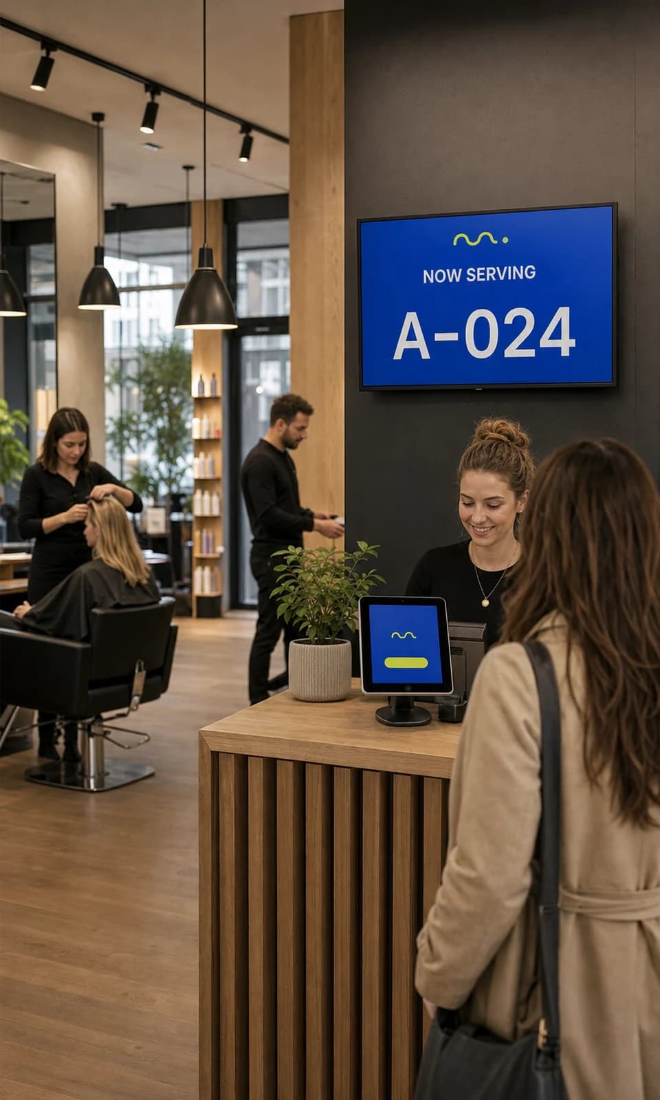 A working salon with Rowomat visible on the reception tablet and queue TV